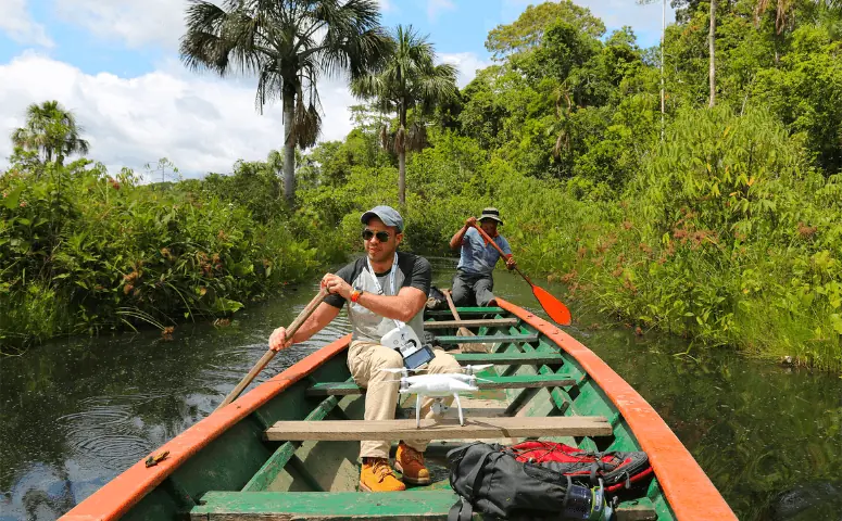 traveler in wooden boat surrounded by jungle